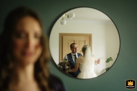 An emotional moment captured during bridal prep in Sheffield, UK, as the bride and her father share a first look in the mirror, with her sister in the background.